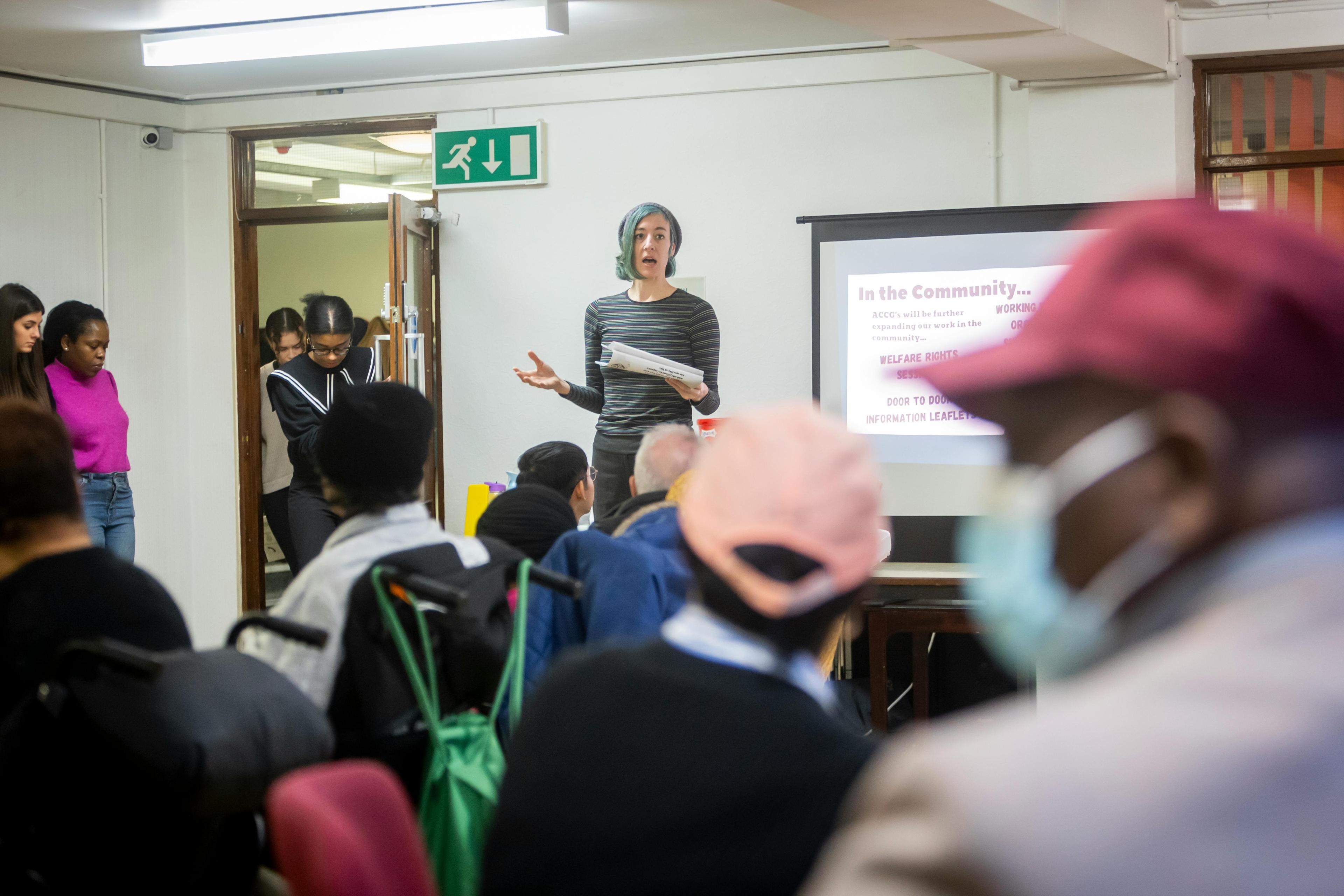 A presenter speaking to a diverse community group seated and listening attentively